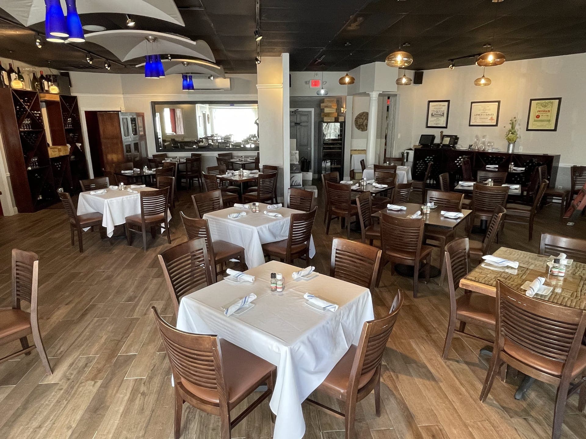 Brandani's Restaurant dining room with white tablecloths, wooden chairs, and blue pendant lighting